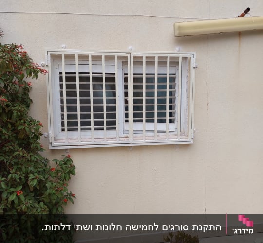 חלון עם סורגים לבנים על קיר חיצוני